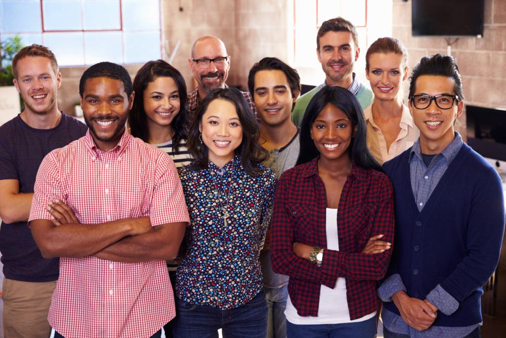 Client Success Stories - Portrait of multicultural staff standing and smiling in a modern design office.