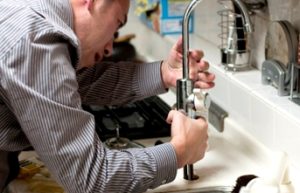 Made in the Trades - A plumber (voluntary trade) works on a sink in a residential building.